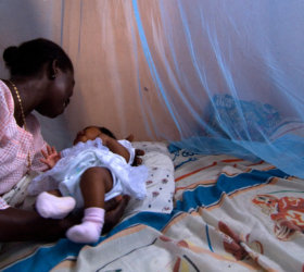 Photo showing a mother and baby behind a protective bed net in Ghana.